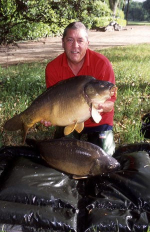 Image of Ken Townley holding a large carp on the lakeside