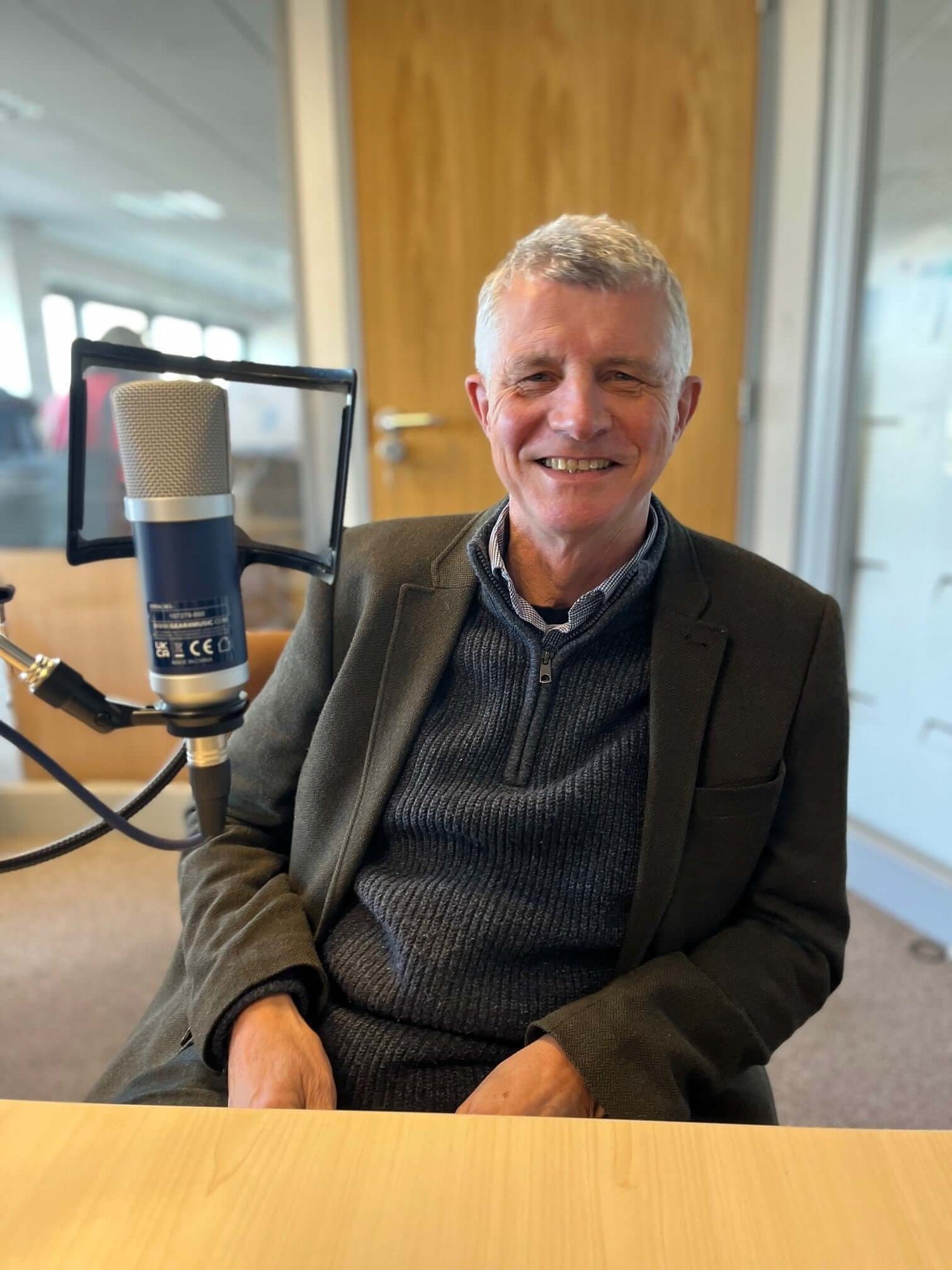 Chris Snell smiling behind a microphone.