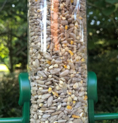 Haith's one for all seed inside a green feeder hanging onto a branch 