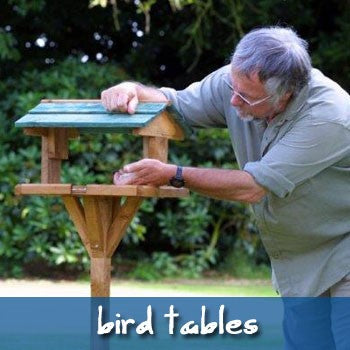 Image of Bill Oddie putting seed on a bird table.