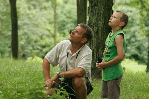 Image of a father & son bird watching in a glade.
