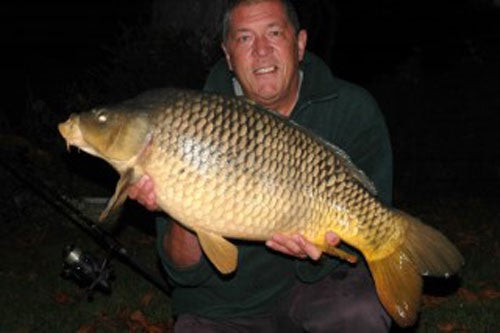 Photo of Ken Townley holding a large carp at night