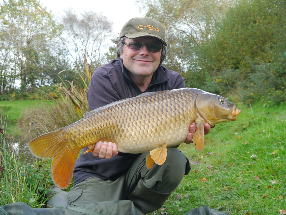 Adam roots holding a large carp at the lakeside