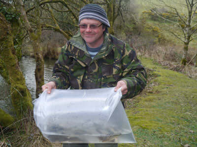 Adam Roots holding fishing bait at the lakeside