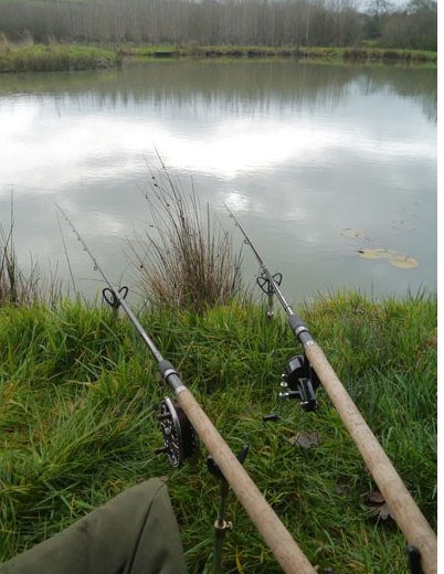 two fishing rods at the side of a lake