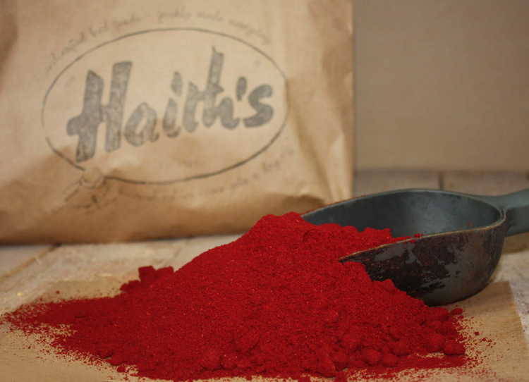 Robin Red fish food on a scoop in front of a bag - premium fishing bait ingredient from Haith's.