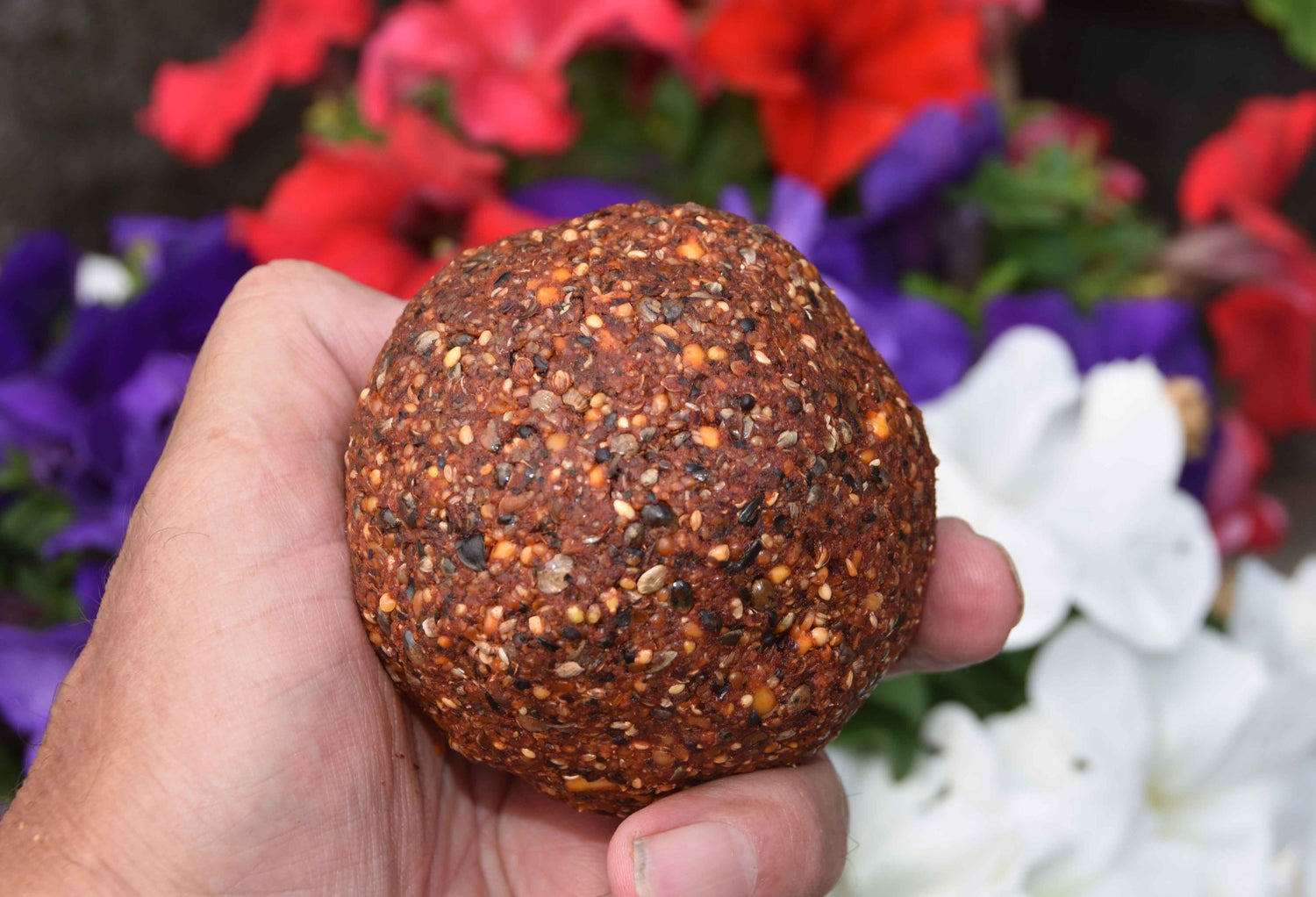 Dark red ground bait in shape of a ball. 