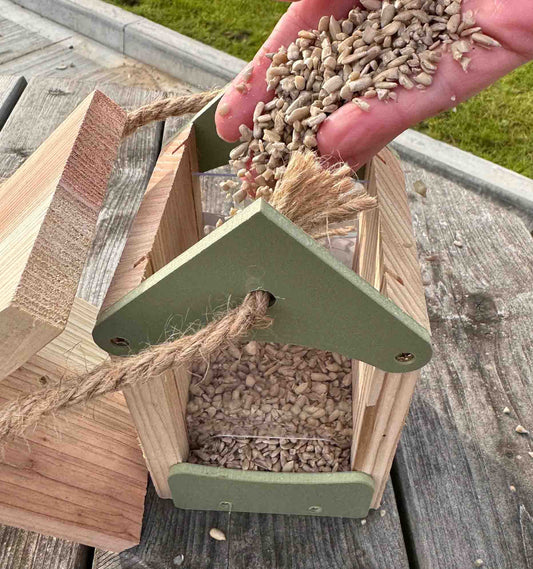 Wooden seed feeder with pitched roof which comes off for easy filling.