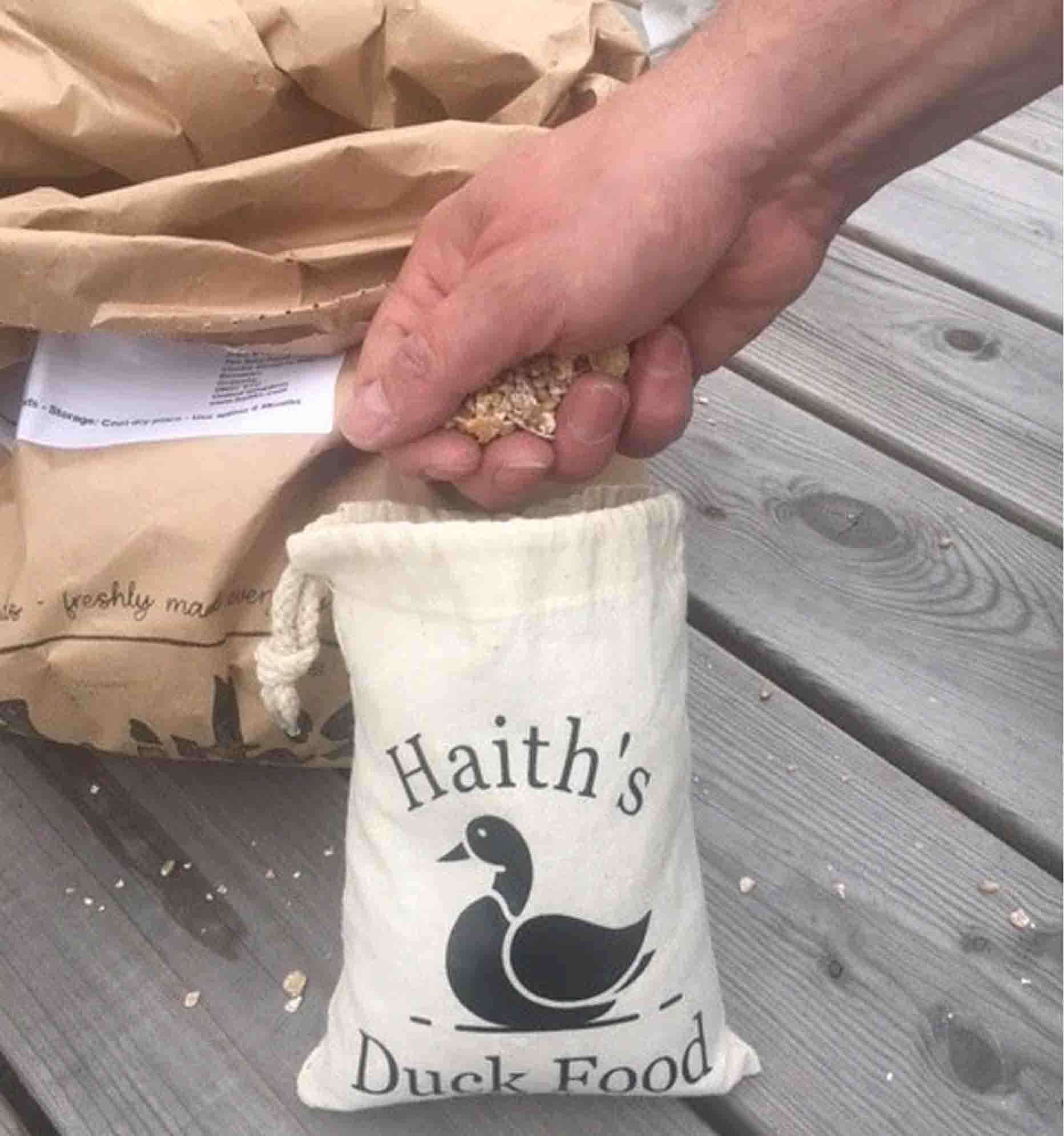 Duck and Goose Mix being taken out of Haith's Duck Food Pouch - a cotton bag with a duck printed on it. 