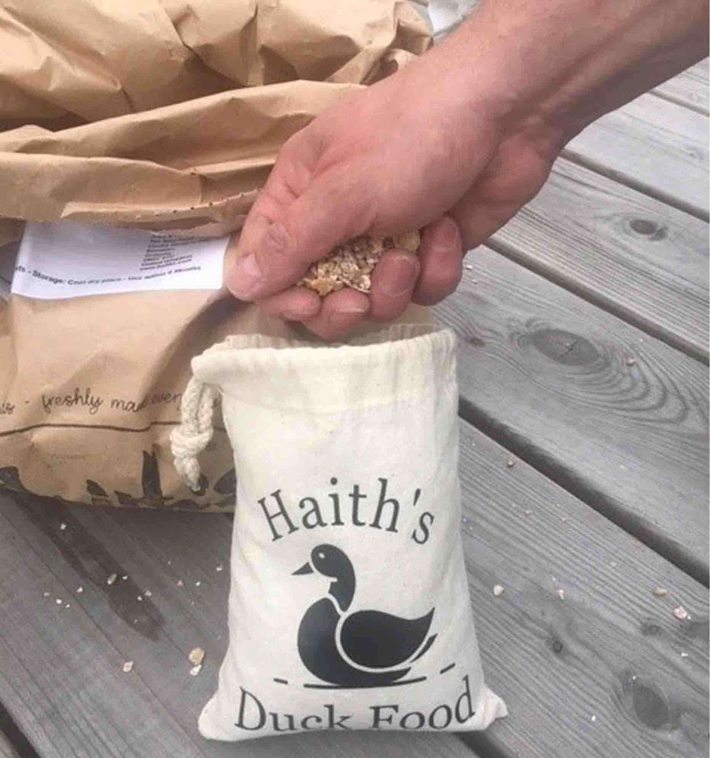 Duck and Goose Mix being taken out of Haith's Duck Food Pouch - a cotton bag with a duck printed on it. 