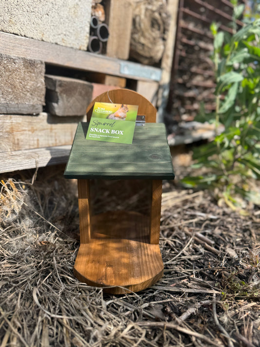 Wooden squirrel feeder with a green label on a natural background
