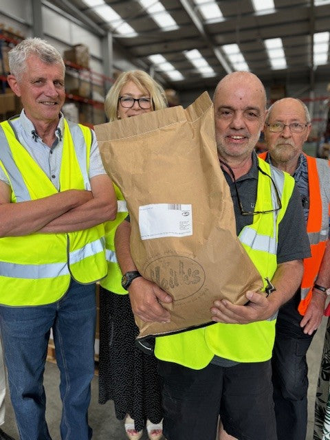 Group of people in a warehouse holding a large brown package.