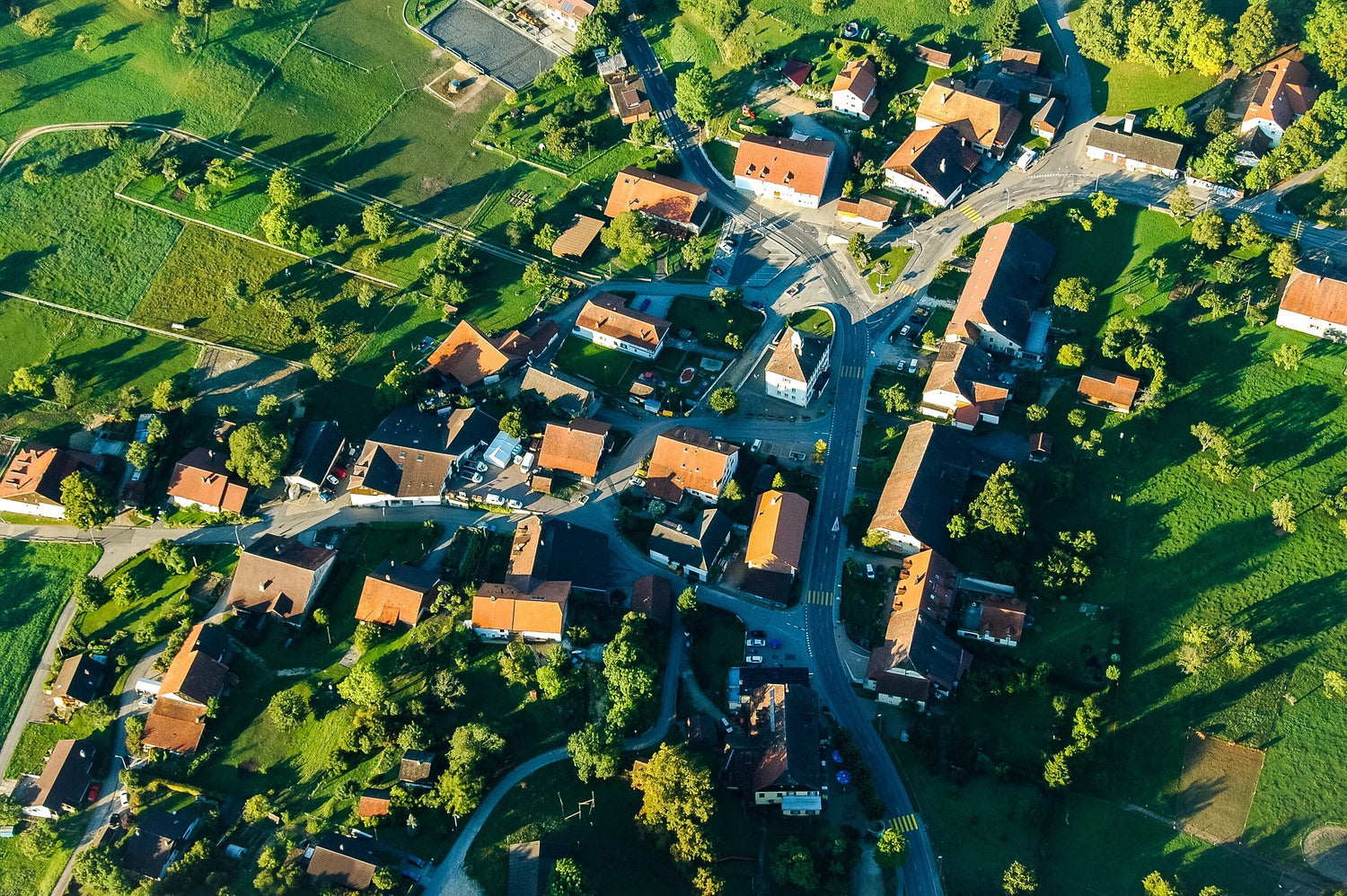 Aerial view of a small village with houses and roads surrounded by greenery.