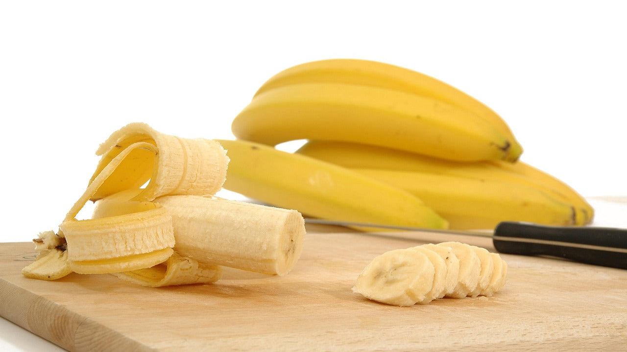 half a banana being chopped up on a wooden chopping board