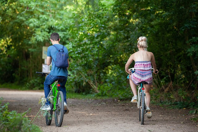 a couple riding bikes through the woods