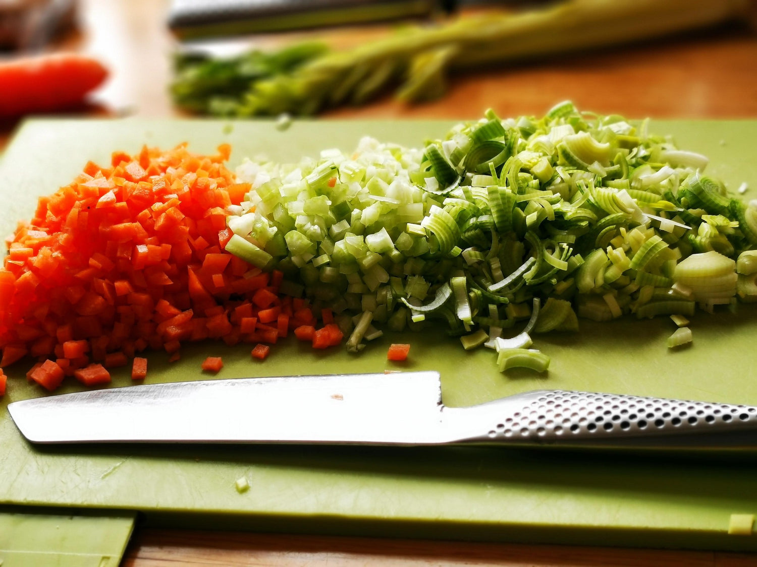 Chopped vegetables on a green cutting board with a knife