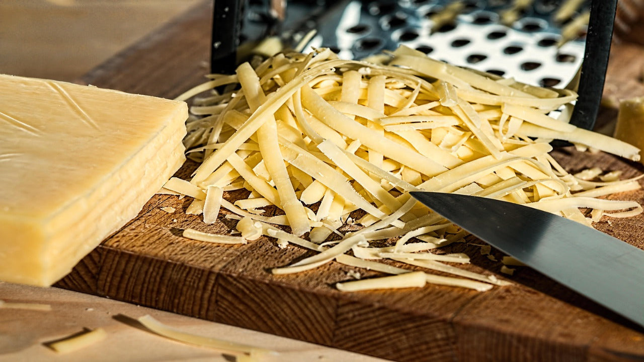 grated cheese on a wooden board with a knife nearby