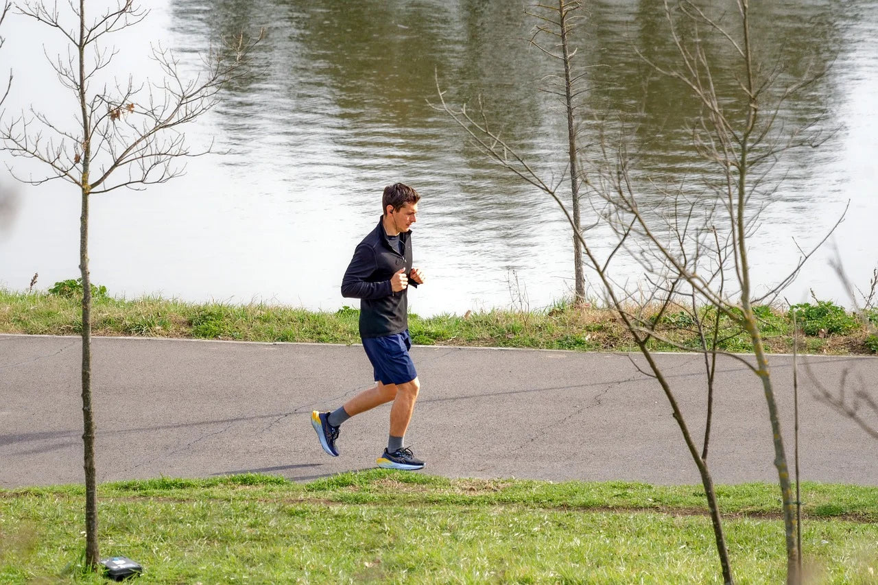 young man jogging in park near to water