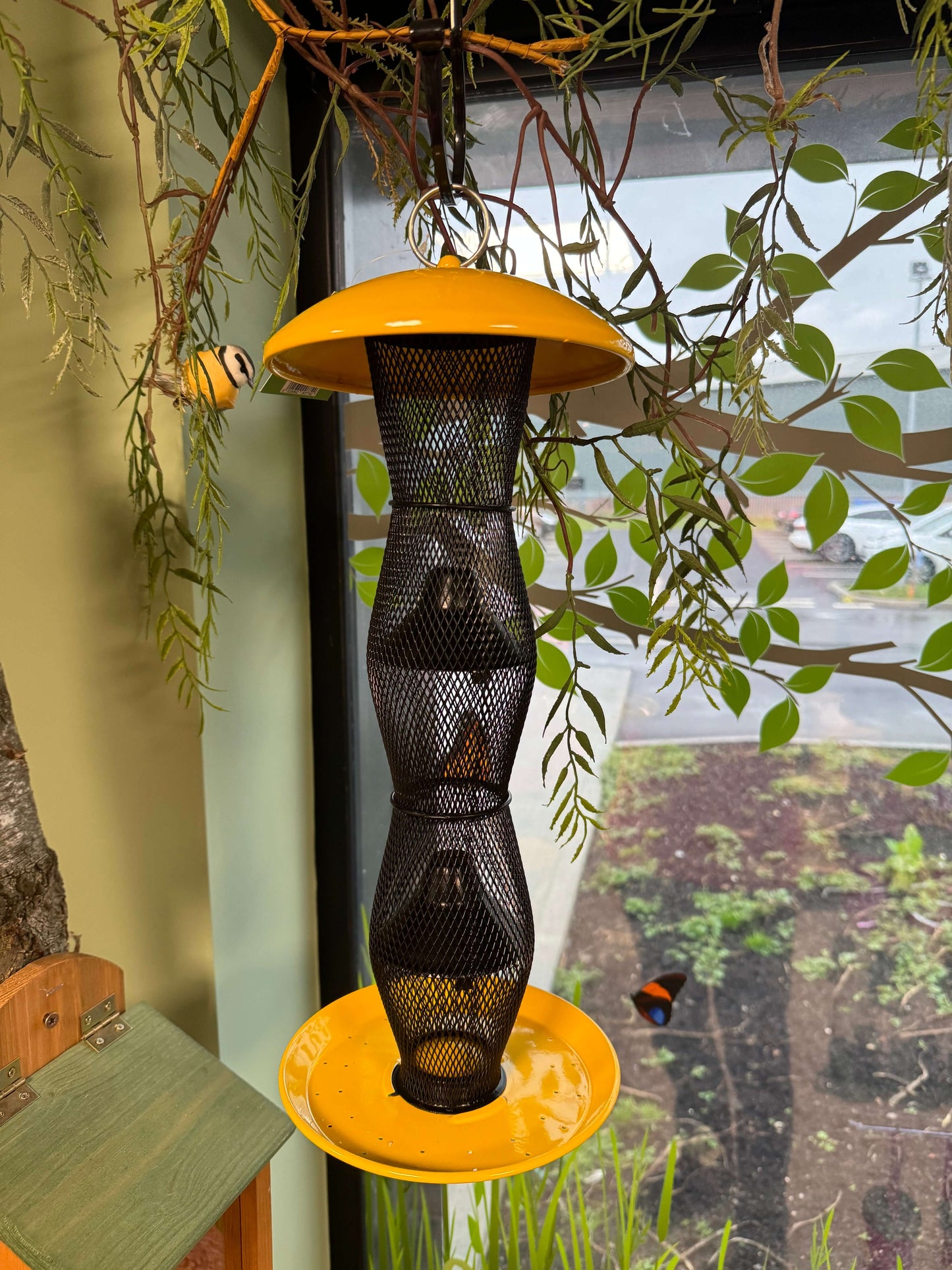 Yellow niger seed feeder with black mesh and built in seed baffles.