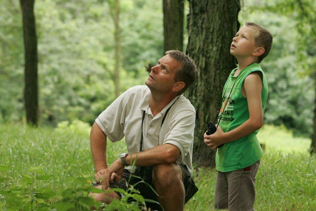 Man and boy birdwatching in woods