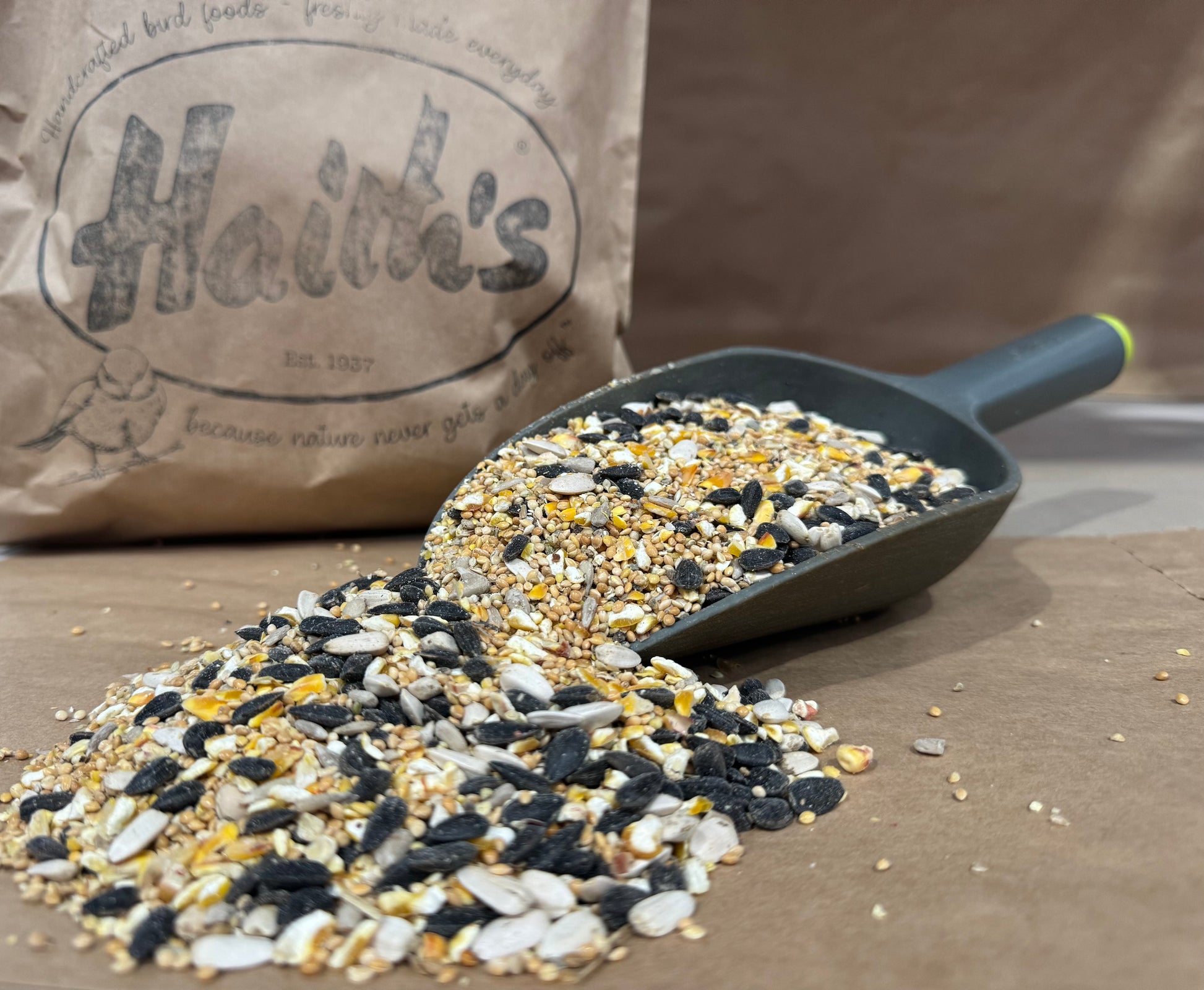 sample of premium wild bird food on a scoop with a haiths bag in the background