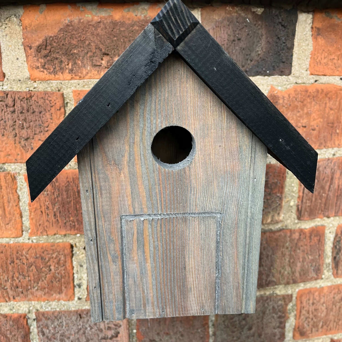Wooden nest box with black, painted roof.